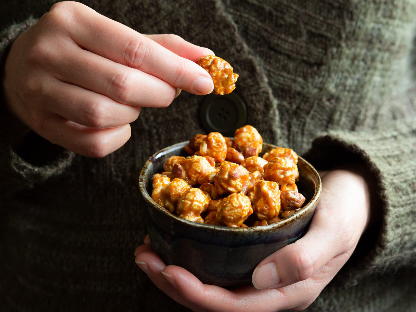 someone holding a bowl of toffee pop gourmet popcorn