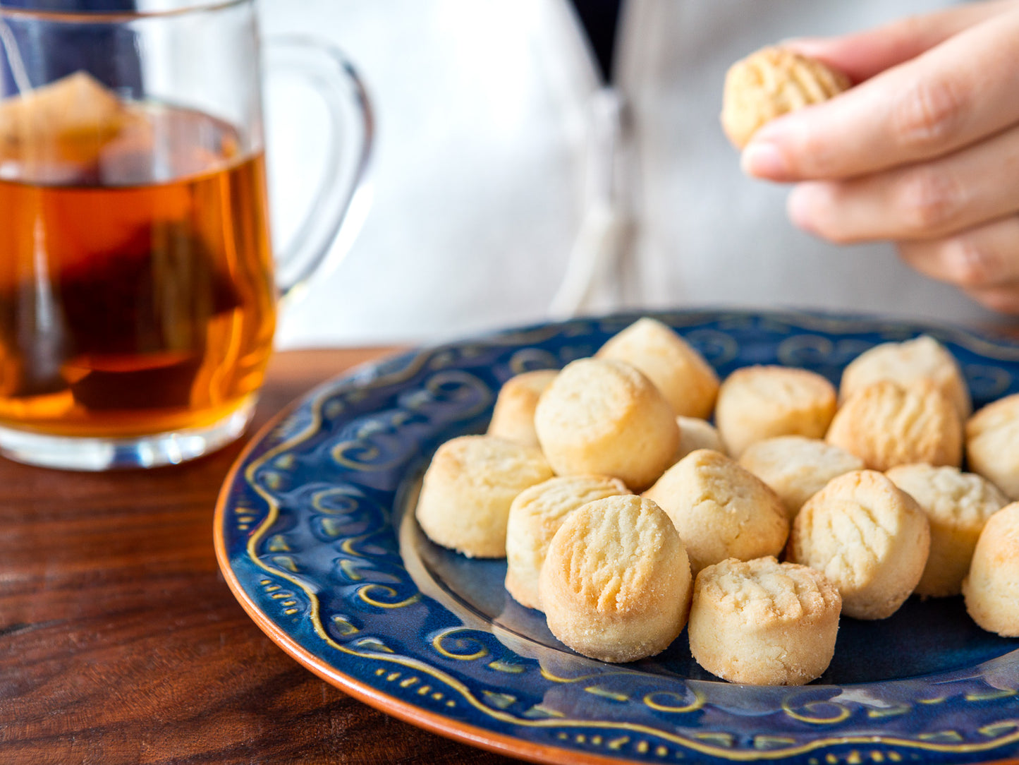 someone enjoying a shortbread cookie with their tea