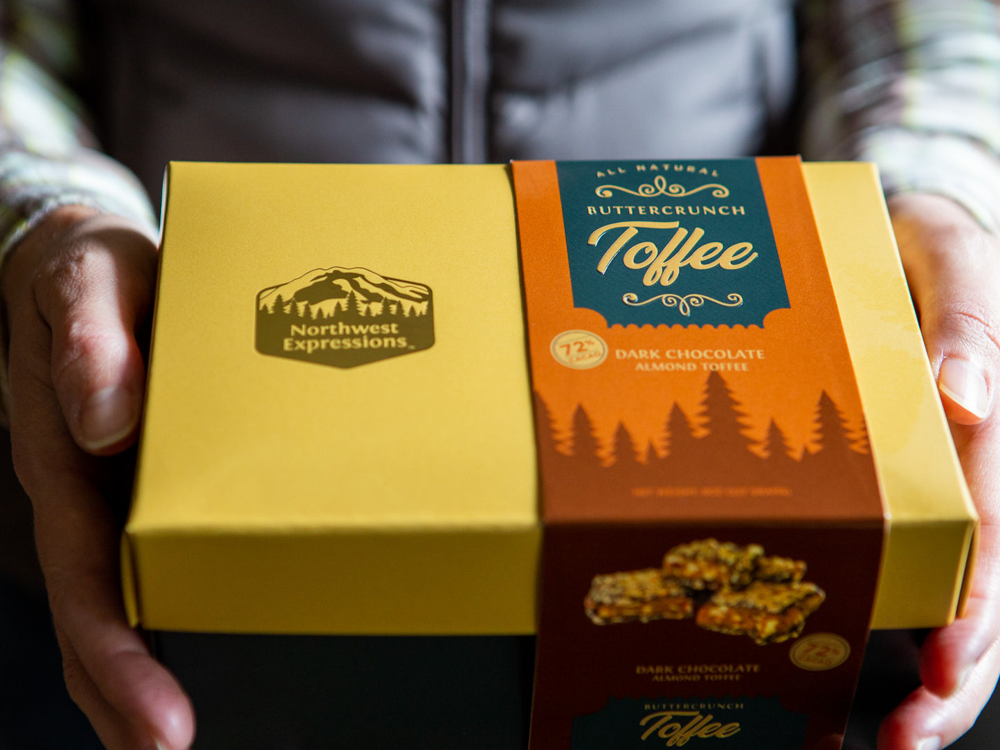 person holding a gift box of toffee in out-stretched hands