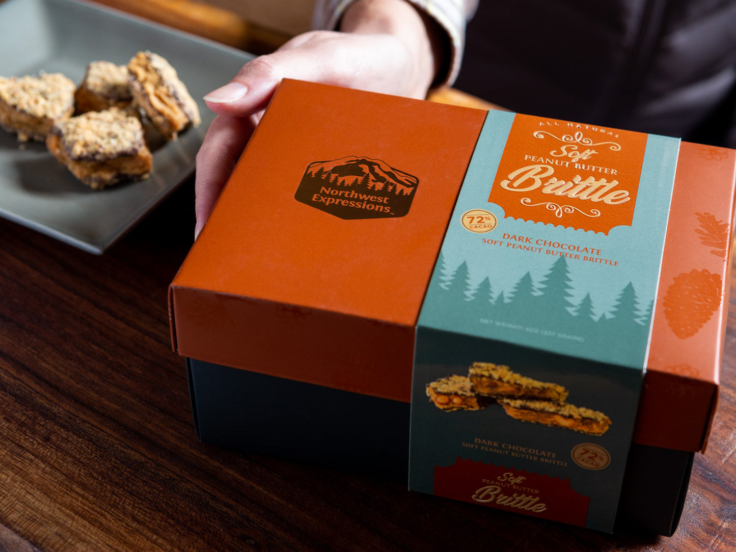 someone holding an elegant gift box of northwest expressions soft peanut butter brittle dipped in dark chocolate